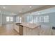 Bright kitchen featuring stainless appliances, white cabinets, an island with sink, and an adjacent living room at 76 Homesite Dulles Dr, Mcdonough, GA 30253