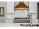 This kitchen features a stainless steel stove, custom vent hood, white cabinets, and gorgeous countertops at 1100 Lady Slipper Way, Canton, GA 30115