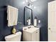 Stylish powder room featuring dark blue walls, modern lighting, and a sleek white vanity with a rectangular mirror at 1320 Country Acres Ln, Lawrenceville, GA 30045