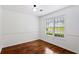 An empty bedroom features a window, hardwood floors, and white walls with decorative molding at 1320 Country Acres Ln, Lawrenceville, GA 30045