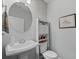 Bathroom with pedestal sink, toilet, white storage cabinet, and decorative round mirror at 2100 Drew Nw Dr, Atlanta, GA 30318