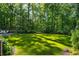 Large backyard featuring a manicured lawn, mature trees, and partial view of the pool at 5360 Lake Forrest Dr, Atlanta, GA 30342