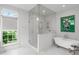 Bright bathroom with a glass-enclosed shower, soaking tub, and a large window with garden view at 5360 Lake Forrest Dr, Atlanta, GA 30342