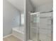 Bright bathroom featuring soaking tub under window, and glass-enclosed shower with chrome fixtures at 2175 Charleston Oak Cir, Lawrenceville, GA 30043