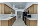 Galley kitchen with wood cabinets, black appliances, light countertops, and light floors at 2175 Charleston Oak Cir, Lawrenceville, GA 30043