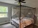 Cozy bedroom with a four-poster bed, soft lighting, and a view of the outdoors at 2298 Hillbriar Dr, Buford, GA 30518