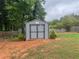 A backyard shed with gray paint and black doors, in a backyard with brown dirt and some grass at 2298 Hillbriar Dr, Buford, GA 30518