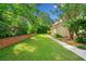 Spacious backyard featuring lush lawn, trees, and partial brick wall at 720 Belgrave Ln, Tucker, GA 30084
