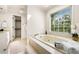 Bathroom featuring a soaking tub under a large window and white cabinets at 720 Belgrave Ln, Tucker, GA 30084