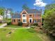 Elegant two-story red brick home with dark shutters, bay window, landscaped front yard, and a classic design at 720 Belgrave Ln, Tucker, GA 30084