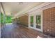 Covered brick back porch with wood-look tile flooring and double doors at 2133 Bird Ln, Snellville, GA 30078