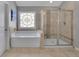 Bright bathroom featuring a soaking tub, a glass-enclosed shower, and a stained glass window at 4100 Secret Shoals Way, Buford, GA 30518