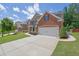 Wide concrete driveway leads to a brick facade home with a two-car garage, complemented by manicured landscaping at 4100 Secret Shoals Way, Buford, GA 30518