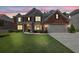 Charming two-story home featuring a well-manicured lawn, brick and stone accents, and an attached two-car garage at 4100 Secret Shoals Way, Buford, GA 30518
