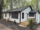Charming home featuring a white exterior, dark trim, a dark roof, and a small wooden porch at 12836 Cumming Hwy, Canton, GA 30115