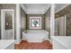 Bright bathroom with marble-surround tub, mosaic window, gold-trimmed shower and patterned wallpaper at 3018 Saint Andrews Ct, Jonesboro, GA 30236