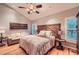 Bright main bedroom with wood headboard, hardwood floors, natural light, and comfortable seating area at 507 Falls Way, Woodstock, GA 30188
