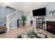 Cozy living room with light-colored walls, wood floors, staircase, fireplace, and large TV screen at 7244 Rockhouse Rd, Austell, GA 30168