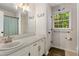 Bright bathroom with white vanity, a framed mirror, and a large window offering natural light at 1027 Spring Mill Sw Dr, Lilburn, GA 30047