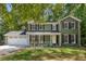 Charming two-story home featuring an inviting front porch, an attached two-car garage, and mature trees at 1027 Spring Mill Sw Dr, Lilburn, GA 30047