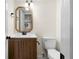 Bathroom features wood vanity and mirror, white walls and toilet and black hardware at 1275 Muirforest Way, Stone Mountain, GA 30088
