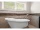 A freestanding bathtub is positioned in front of a window with privacy blinds at 5816 Chamblee Dunwoody Rd, Atlanta, GA 30338