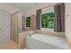 Bright bathroom features a glass-enclosed shower and a soaking tub by the window at 7940 Gable Dr, Douglasville, GA 30135