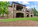 Expansive backyard featuring a stone patio, lush green lawn, and stunning brick architecture at 878 Middle Fork Trl, Suwanee, GA 30024