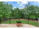 Backyard features a stone patio, black metal fencing, lush green lawn, and wooded perimeter at 878 Middle Fork Trl, Suwanee, GA 30024