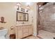 Bathroom with a single sink vanity with framed mirror, decorated with a cowboy boot and a glass enclosed tiled shower at 878 Middle Fork Trl, Suwanee, GA 30024
