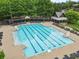 Large community swimming pool with lane markers, lounge chairs, and shaded seating areas at 878 Middle Fork Trl, Suwanee, GA 30024