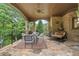 Backyard covered patio features ceiling fan, stone floor, comfortable seating, and beautiful backyard at 878 Middle Fork Trl, Suwanee, GA 30024