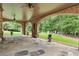 Inviting covered patio with stone flooring, brick pillars, ceiling fans, and lush green backyard at 878 Middle Fork Trl, Suwanee, GA 30024