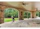 Spacious covered patio featuring stone flooring, brick arches, ceiling fans and backyard views at 878 Middle Fork Trl, Suwanee, GA 30024