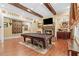 Spacious game room featuring a pool table, hardwood floors, wood beams, and a cozy fireplace at 878 Middle Fork Trl, Suwanee, GA 30024