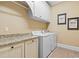 Well-lit laundry room featuring white cabinets, granite countertops, and modern washer and dryer at 878 Middle Fork Trl, Suwanee, GA 30024