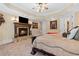 Carpeted primary bedroom featuring a large fireplace, tray ceiling, and decorative lamps at 878 Middle Fork Trl, Suwanee, GA 30024