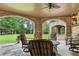 Covered patio featuring stone flooring, multiple chairs and lush backyard views at 878 Middle Fork Trl, Suwanee, GA 30024