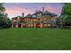 Expansive backyard with a covered patio of an elegant stone home at sunset at 878 Middle Fork Trl, Suwanee, GA 30024
