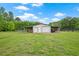 Outbuilding featuring two garage doors and a carport, surrounded by green lawn and trees on a sunny day at 24 Fossetts Nw Cv, Cartersville, GA 30121