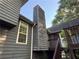 View of the home's exterior with gray siding, a towering chimney, and a deck with stairs at 1100 Whistle Dr, Austell, GA 30106