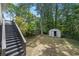 Backyard featuring a shed, black stairs, wooded surroundings and a well-maintained lawn at 1505 Cedar Bluff Trl, Marietta, GA 30062