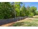 This image shows a large backyard with a dark brown fence and a path leading into a lush green forest at 3723 Silvery Way, Powder Springs, GA 30127