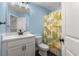 Bathroom with blue walls, white vanity, and banana-themed shower curtain at 3723 Silvery Way, Powder Springs, GA 30127