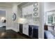A stylish bar area with white cabinets, marble backsplash, wine cooler, and a view into an adjacent dining room at 9675 Almaviva Dr, Alpharetta, GA 30022