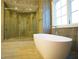 Modern bathroom featuring a freestanding tub, glass shower with tile surround, and large window with natural light at 9675 Almaviva Dr, Alpharetta, GA 30022