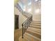 Beautiful staircase with decorative iron railings, light wood steps, and elegant wall paneling with inset lighting at 9675 Almaviva Dr, Alpharetta, GA 30022