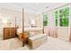 Charming bedroom with a four-poster bed, patterned wallpaper, tray ceilings, and natural light from large windows at 1996 Cobblestone Ne Cir, Atlanta, GA 30319