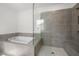 Modern bathroom featuring a walk-in shower with gray tile, bench, and separate soaking tub at 6660 Wallace Farms Dr, Cumming, GA 30028