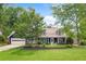 Charming home featuring a well-maintained lawn, lush trees, and a welcoming exterior with a two-car garage at 209 Hearthstone Reach, Peachtree City, GA 30269